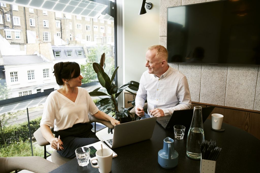 man and woman behind laptop having a meeting