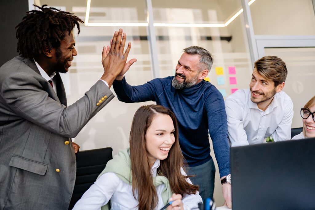 highfive at the office behind screen group of employees